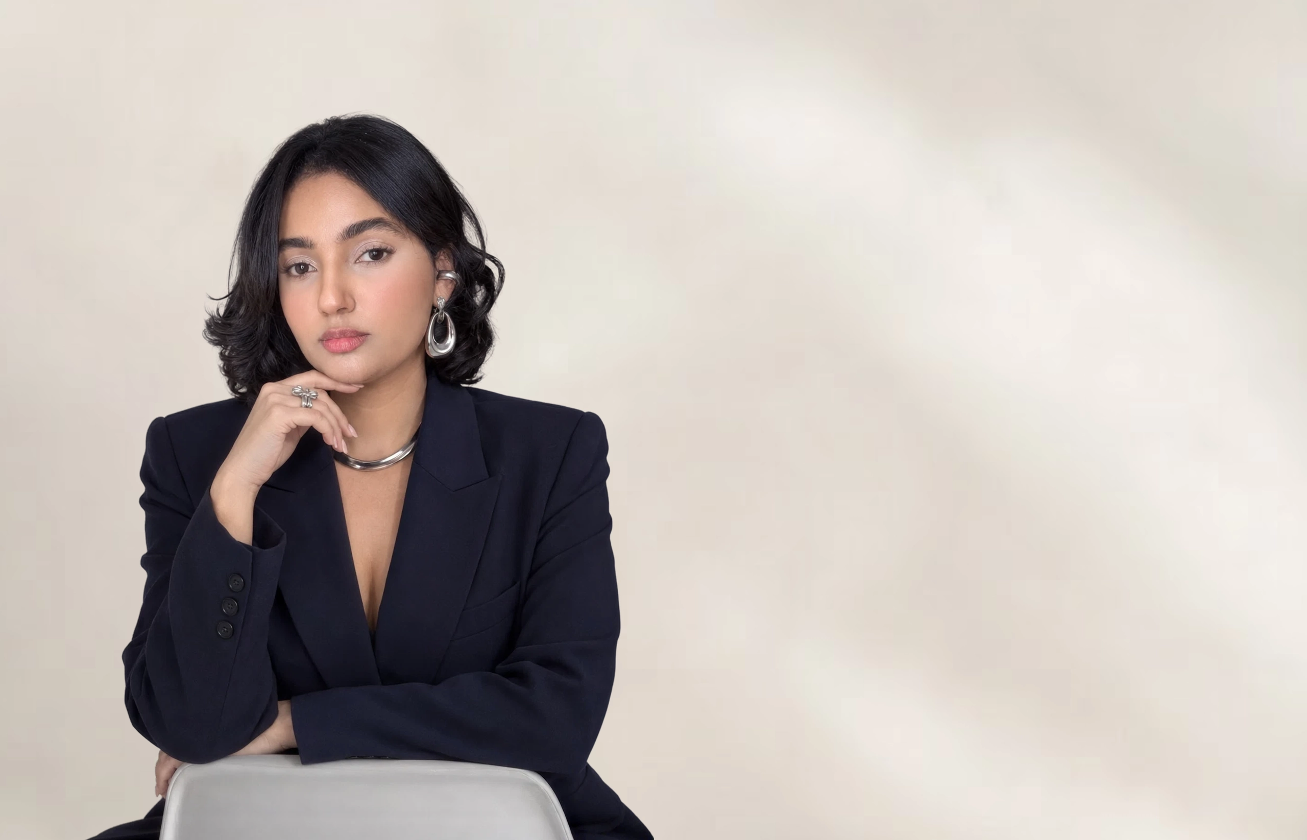Karen Voguedo con blazer negro, apoyada en el respaldo de una silla.